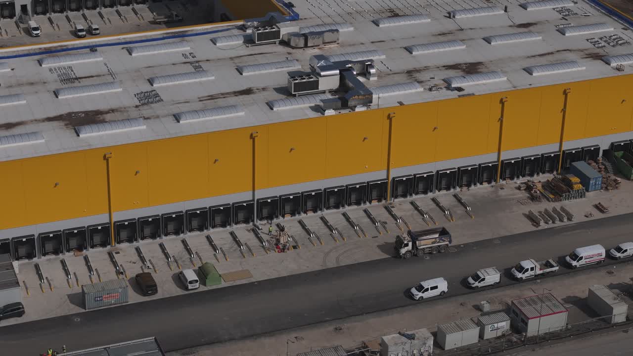 Industrial warehouse and yard operations support large scale distribution, with goods handling and transport flows connected to A1 major motorway corridor in Po Valley, Italy, drone panning