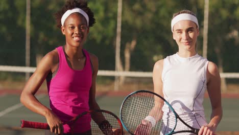 Video-Von-Glücklichen,-Vielfältigen-Tennisspielerinnen,-Die-Schläger-Halten-Und-In-Die-Kamera-Schauen
