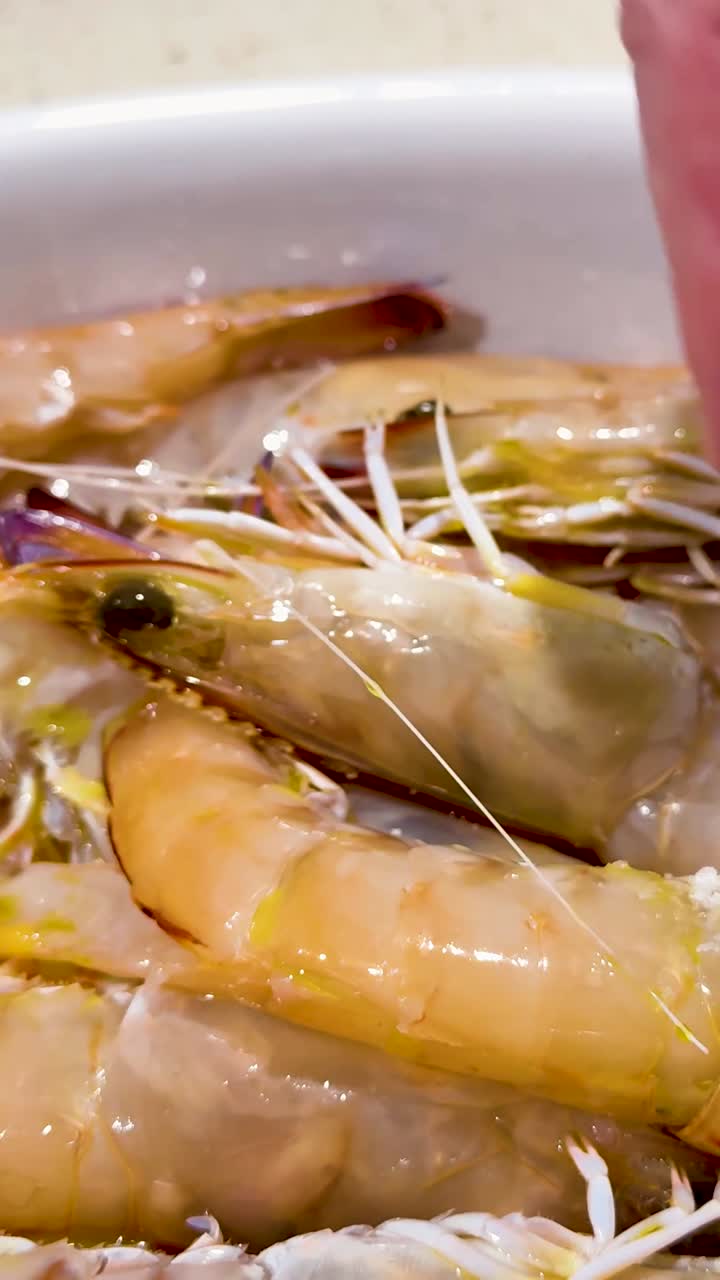 손은 그에 있는 신선한 새우 위에 소금을 뿌립니다.