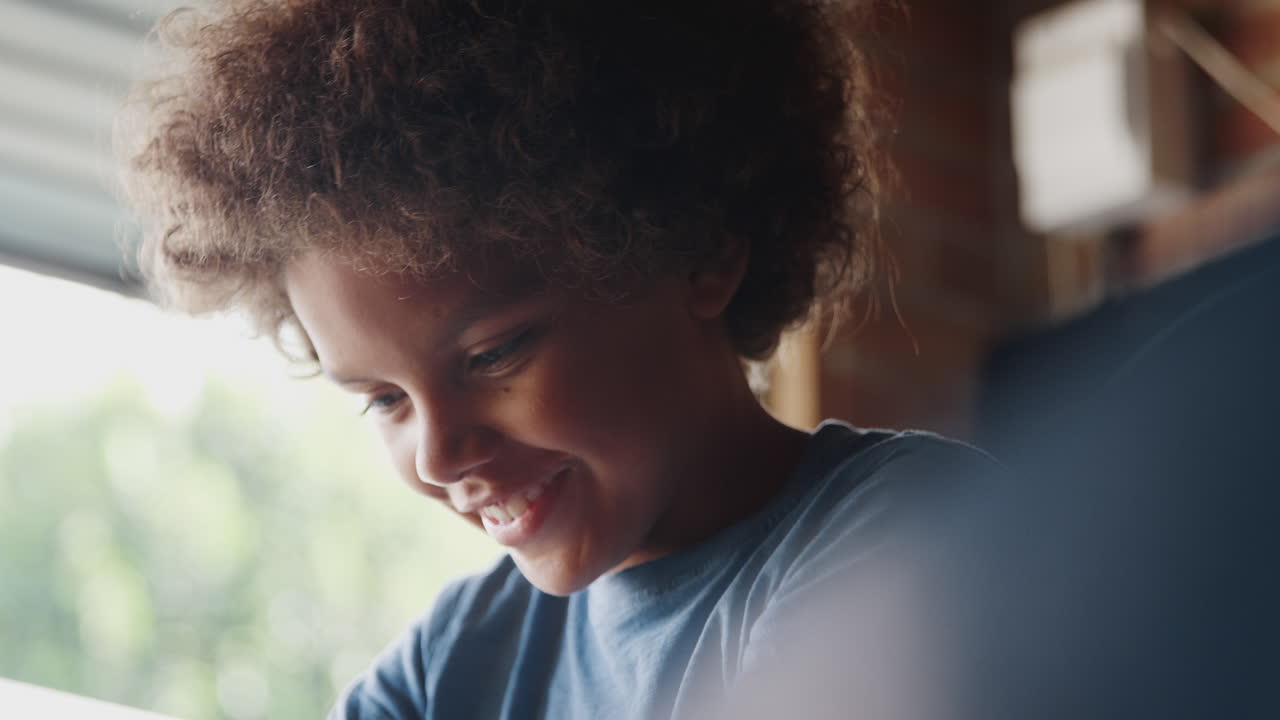 cabeza y hombros de cerca de un feliz pre-adolescente hablando mientras trabaja en su kart en el garaje, retroiluminado