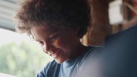 head and shoulders close up of happy pre teen boy talking as he works on his kart in the garage, backlit