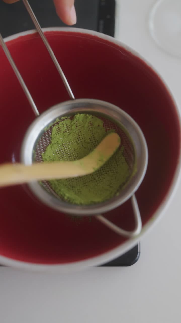 Sifting Matcha Powder into a Red Bowl