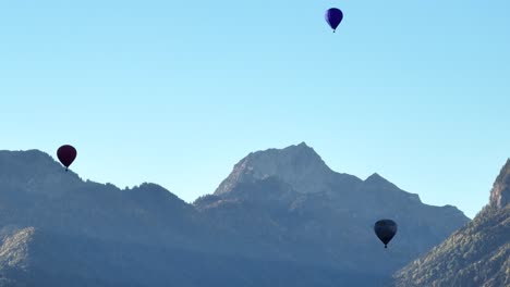 three hot air balloons flying over the mountains in the french alps