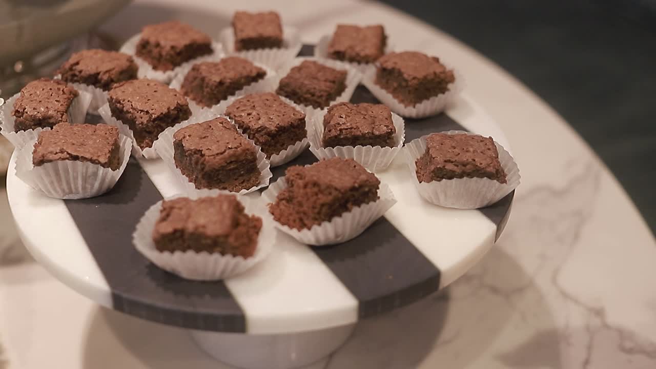 una joven toma un plato redondo con brownies horneados, deliciosas galletas de chocolate, toma de cerca