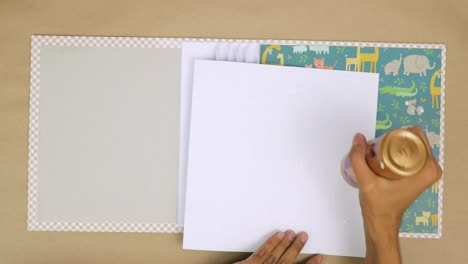 aplicar el tipo correcto de pegamento para asegurar los elementos decorativos en un libro de recortes para bebés