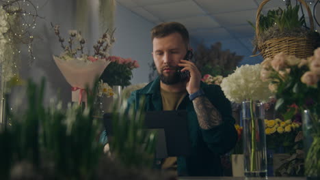 female florist talks by phone with customer and uses tablet