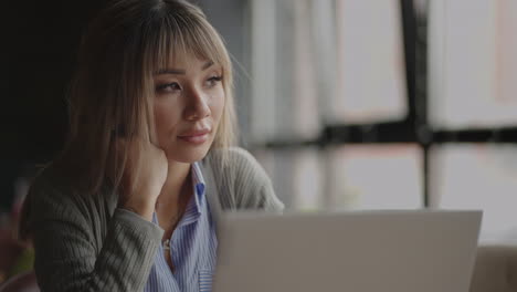 Una-Joven-Asiática-Extraña-Mirar-Su-Computadora-Portátil.-Retrato-De-Un-Estudiante-Asiático-Cansado