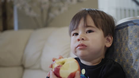 un niño pequeño come una gran manzana roja