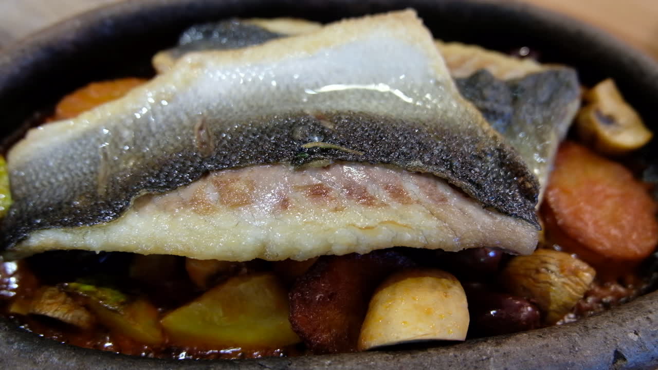 Close up of a fish filet cooking with potatoes