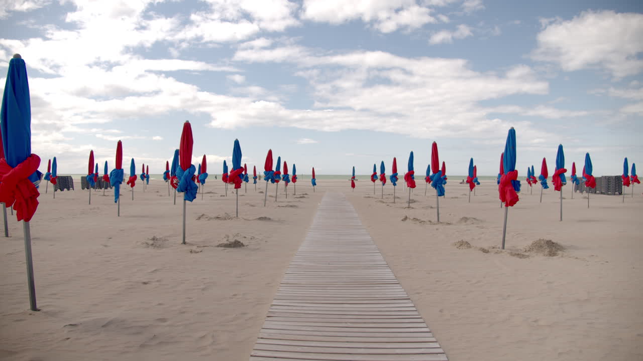 산책로가 있는 빈 해변의 닫힌 비치 파라솔