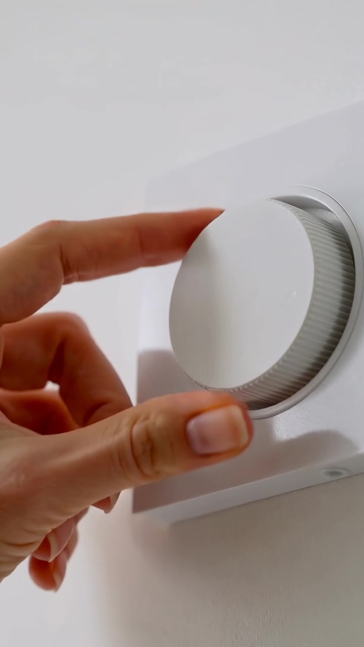 Video verticale: Una mano che ruota dopo aver toccato e regolato una manopola con bordo metallico per cambiare la temperatura a casa.