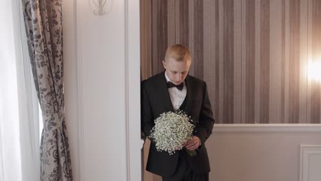a groom waiting with a bouquet of white flowers