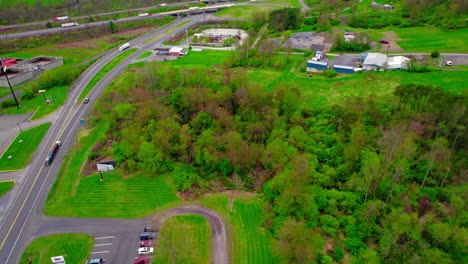 Springtime-aerial-view-of-a-pickup-truck-pulling-a-wedge-trailer-with-cars-on-a-rural-highway,-illustrating-the-car-hauling-industry