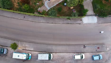 aerial view of a curving street with parked cars and a person walking