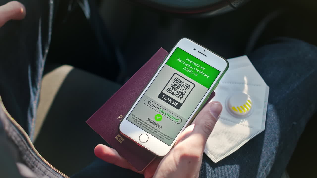 CHISINAU, MOLDOVA - APRIL 15, 2020: Man holding mask, passport and smartphone with International Vaccination Certificate COVID-19 QR code in a car and going out