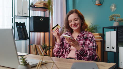 Woman-using-bank-credit-card-and-smartphone-for-online-shopping-payments-transaction-at-home-office