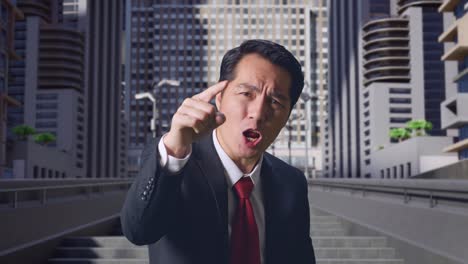 분노 한 아시아 사업가 가 도시 에서 서 있는 동안 비난 하고 있다