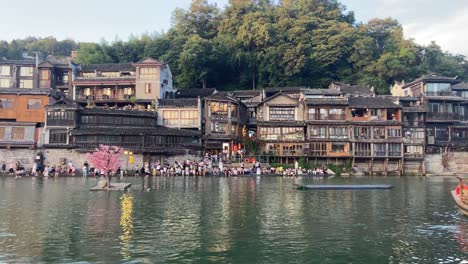 wharf full of tourists in traditional chinese village of fenghuang at sunset