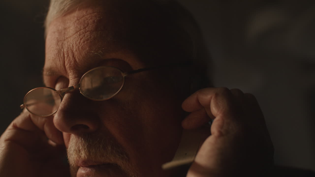 Older passionate man evaluates an old watch in his office at night