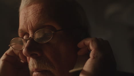older passionate man evaluates an old watch in his office at night