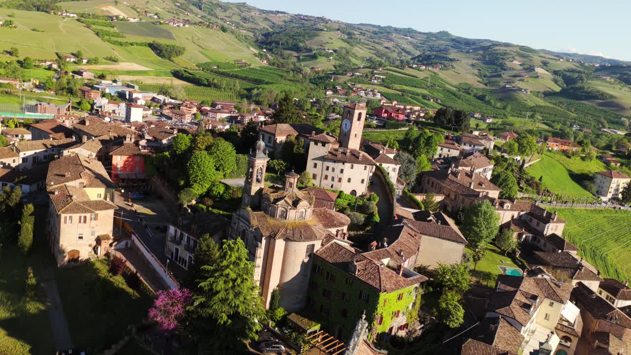 Historic hilltop village of Neive in Piedmont, Italy, ancient buildings, tower, and surrounding green landscape. Aerial drone backward