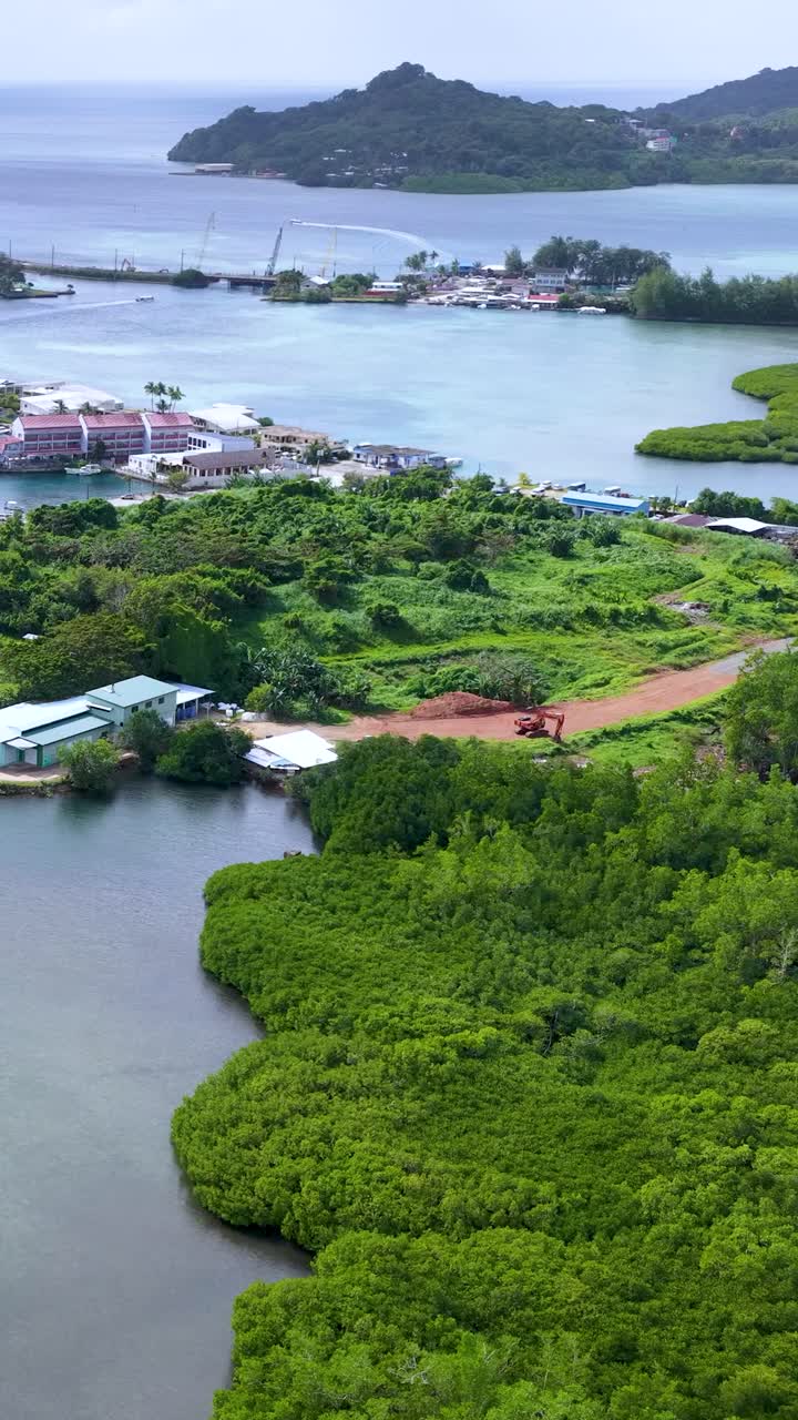 Cảnh quay drone từ trên cao cho thấy một ngôi làng trên đảo nhiệt đới, làn nước xanh ngọc bích và những khu rừng ngập mặn xanh tươi rậm rạp