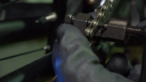 mechanic uses chain break tool to remove link from bike chain, closeup