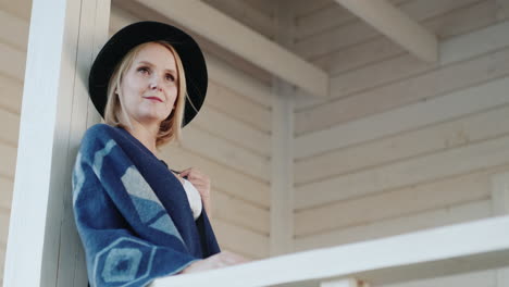 stylish woman in a hat on the terrace of her home