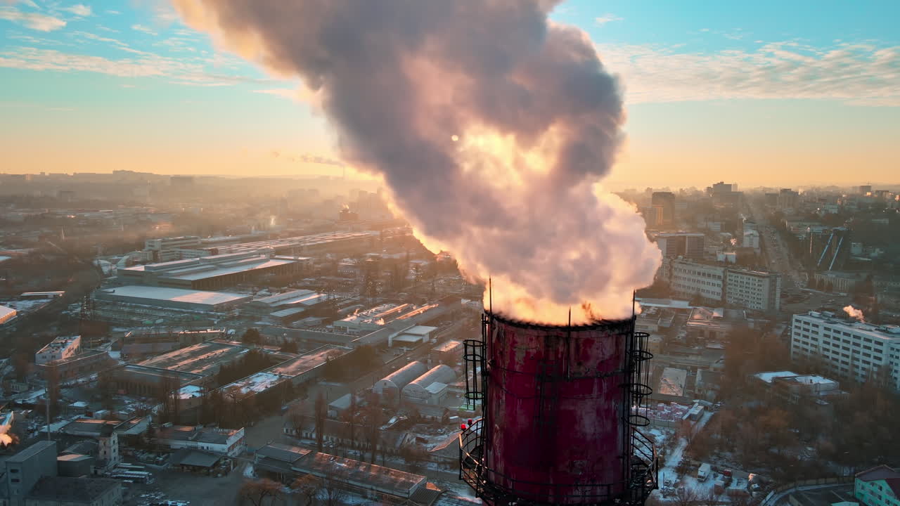 Aerial drone view of Chisinau at sunrise. Thermal station with smoke coming out of the tube. Buildings, roads and bare trees on the background. Good weather, snow on the ground. Moldova