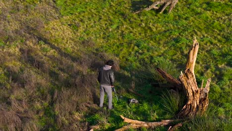 fotógrafo al aire libre junto a la madera de árbol muerto en el paisaje rural