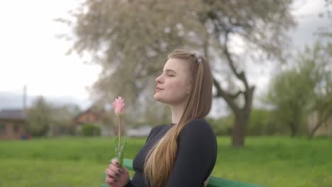 una hermosa chica romántica sostiene un tulipán en sus manos y prueba su fragancia