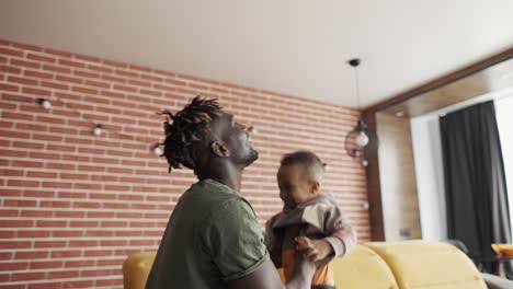 playful father raising his toddler son up in air, slow motion