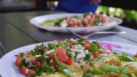 narrow focus: two plates of omelette with greek salad on outdoor table