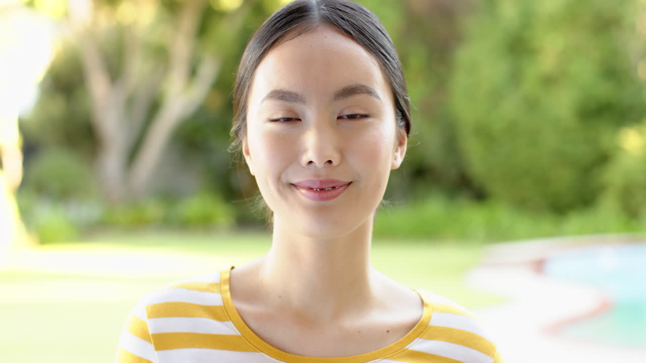 Smiling asian girl with braces wearing striped shirt, enjoying outdoor time