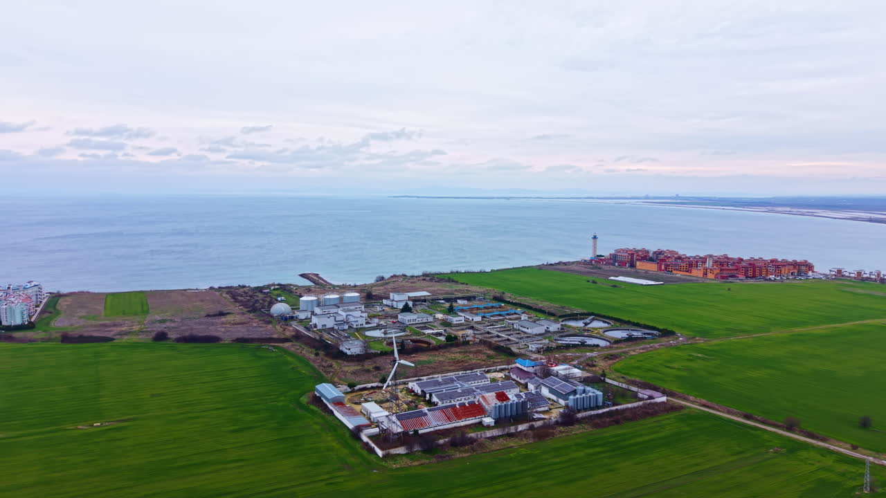 Felder treffen in der Dämmerung in der Nähe eines Leuchtturms und einer kleinen Stadt am Meer auf die Küste
