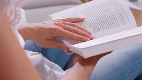 mujer sentada en el sofá leyendo un libro