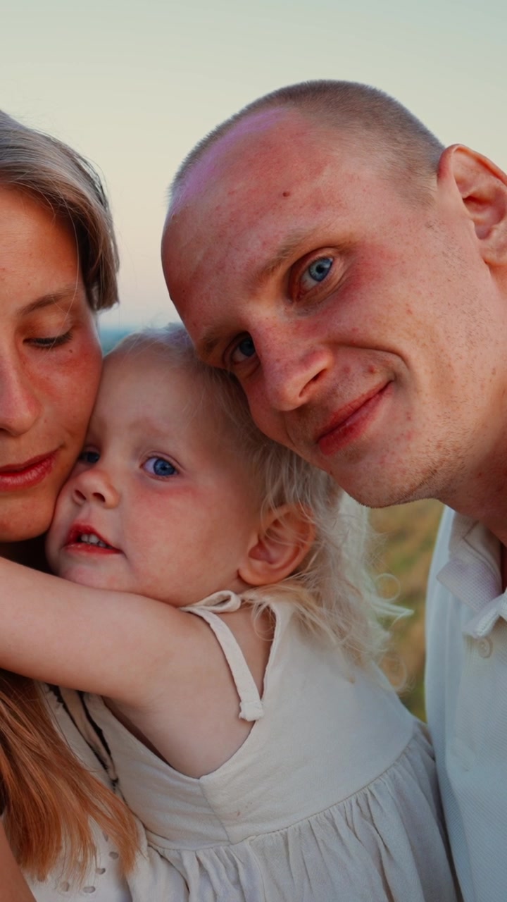 Giovane famiglia che si abbraccia in un campo di grano dorato al tramonto