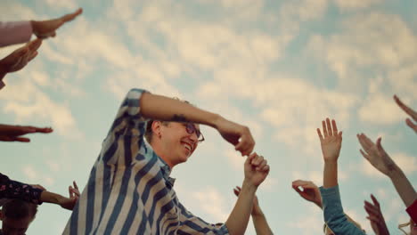 partying people raising hands up outdoors. excited man dancing at party.