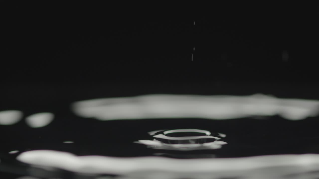 gotas de agua golpean la superficie del líquido causando ondulaciones y pequeñas salpicaduras