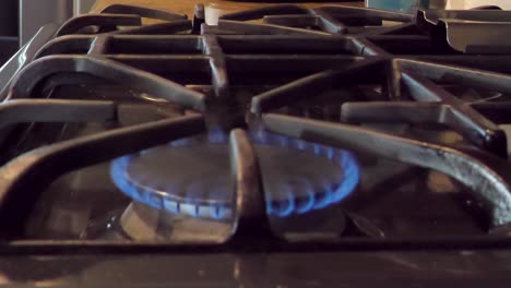 Gas-stove-flame-turning-on-with-frying-pan-put-on-gas-burner,-closeup-slow-motion