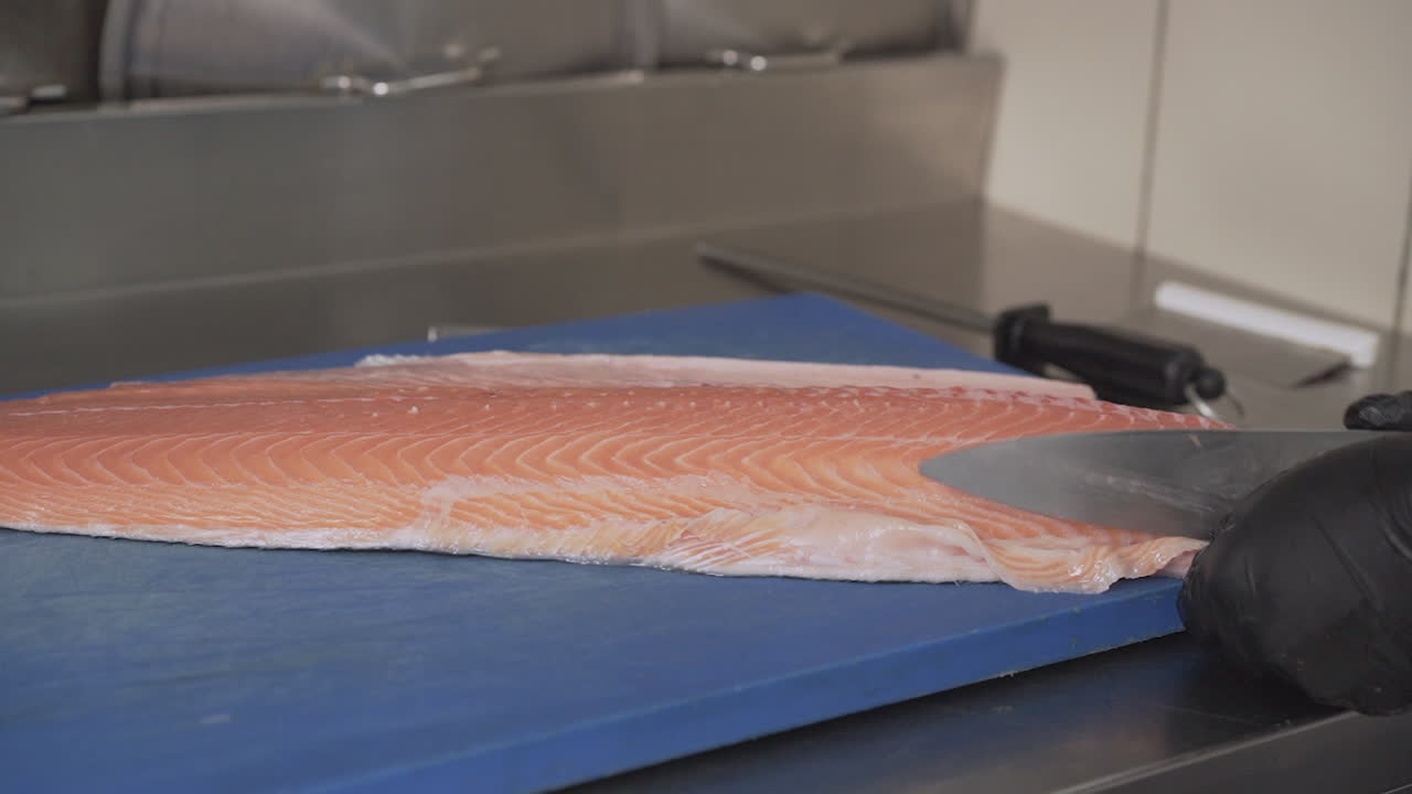 primer plano de un chef la limpieza, preparación y corte de un filete de salmón fresco