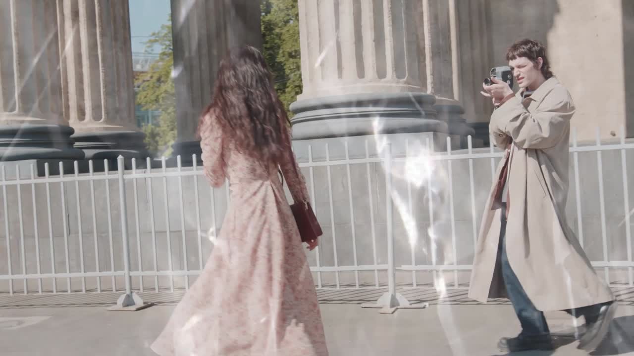 Man Films Woman Posing with Vintage Camera by Classical Columns