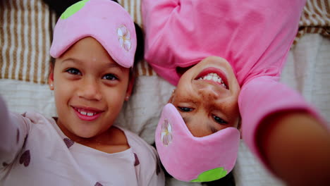 two girls in sleep masks lying down and smiling