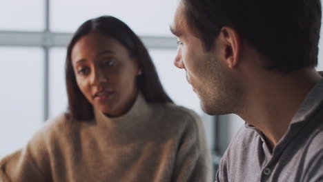 Pull-Focus-Close-Up-Of-Businessman-Working-On-Laptop-At-Desk-With-Female-Colleague