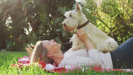 feliz mujer caucásica jugando con su perro en el jardín