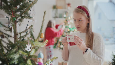 beautiful young woman drinking coffee near christmas tree at home