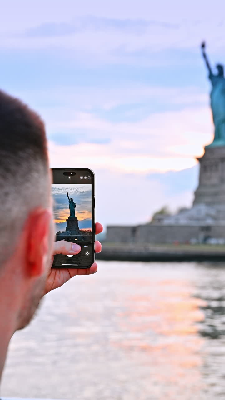 New York, USA, 8 July 2025: Capturing Statue of Liberty. A traveler captures the iconic skyline of New York City during a serene sunset on the water