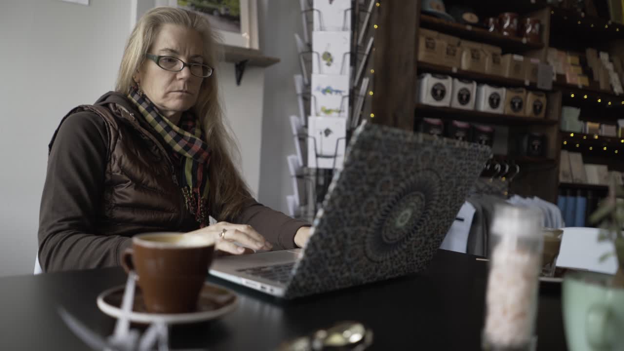 Donna che lavora al computer portatile in un caffè
