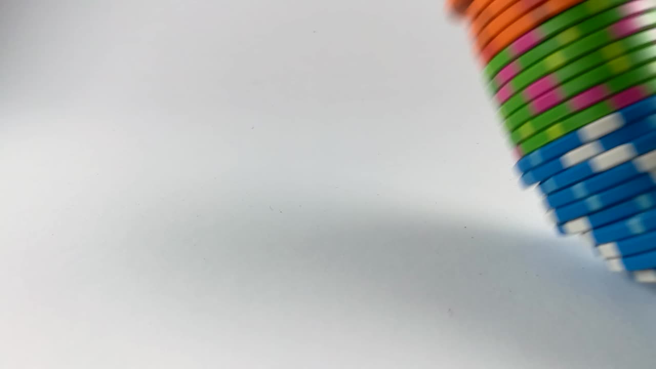 Stack of colorful poker chips falling down from right side on a white table, ISOLATED, STILL, SLOMO