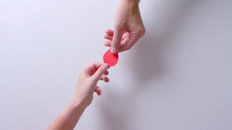 Hands-of-caucasian-people-giving-blood-drop-on-white-background-with-copy-space,-slow-motion